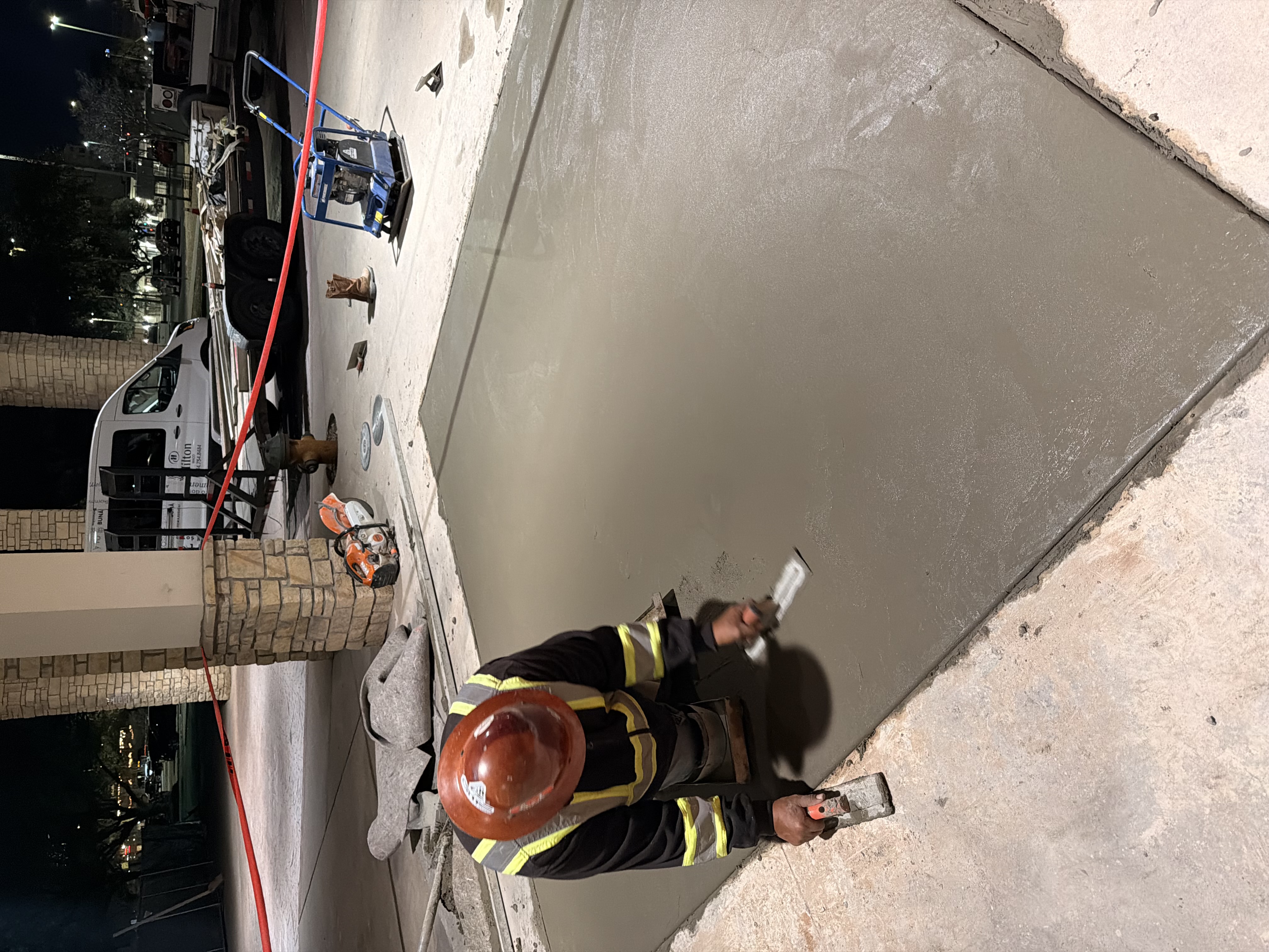 APC crew finishing a commercial concrete surface at night