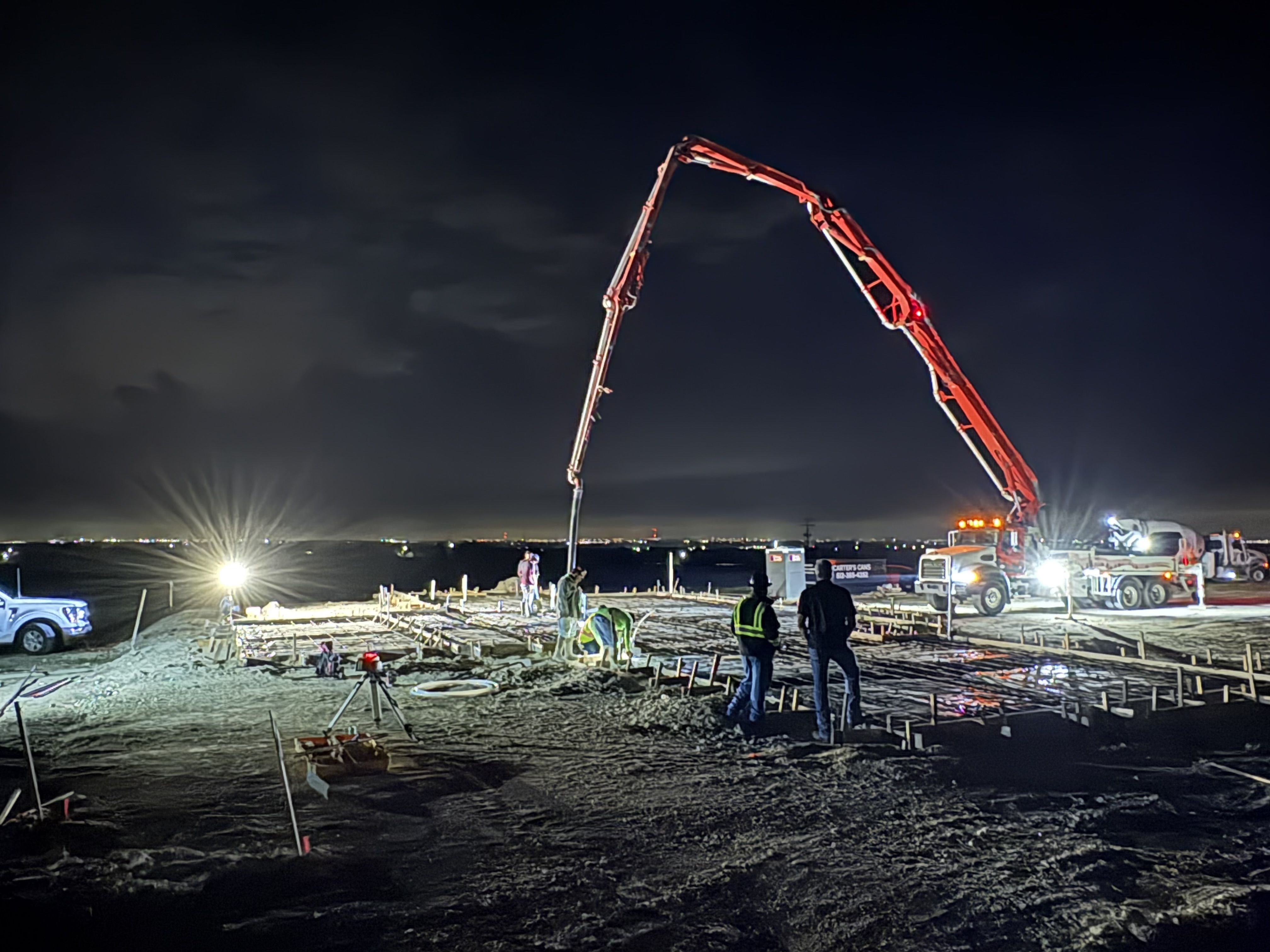 Concrete pump truck pouring a large commercial foundation at night — APC Central Texas