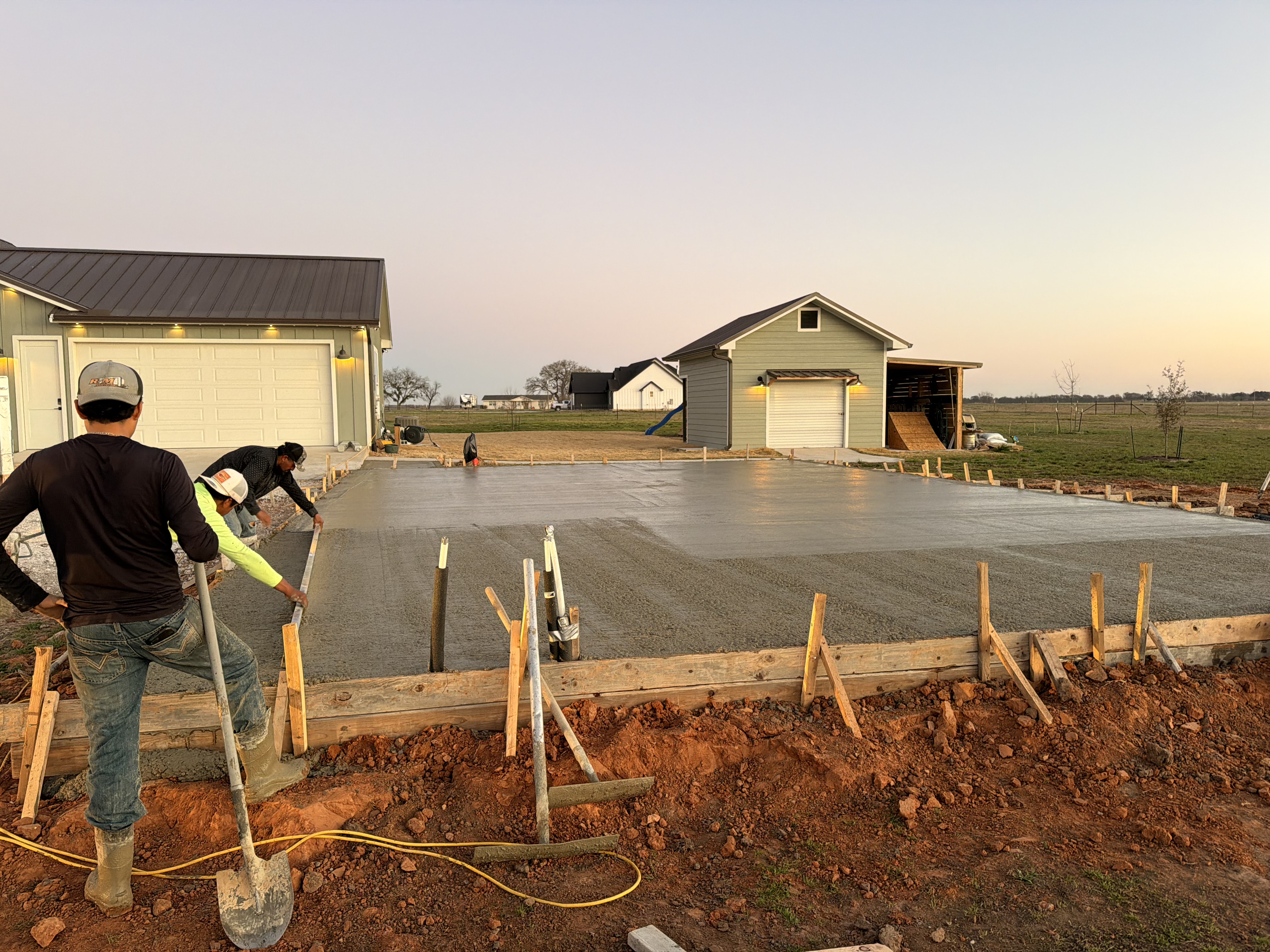 APC crew finishing a residential concrete driveway at dusk in Central Texas